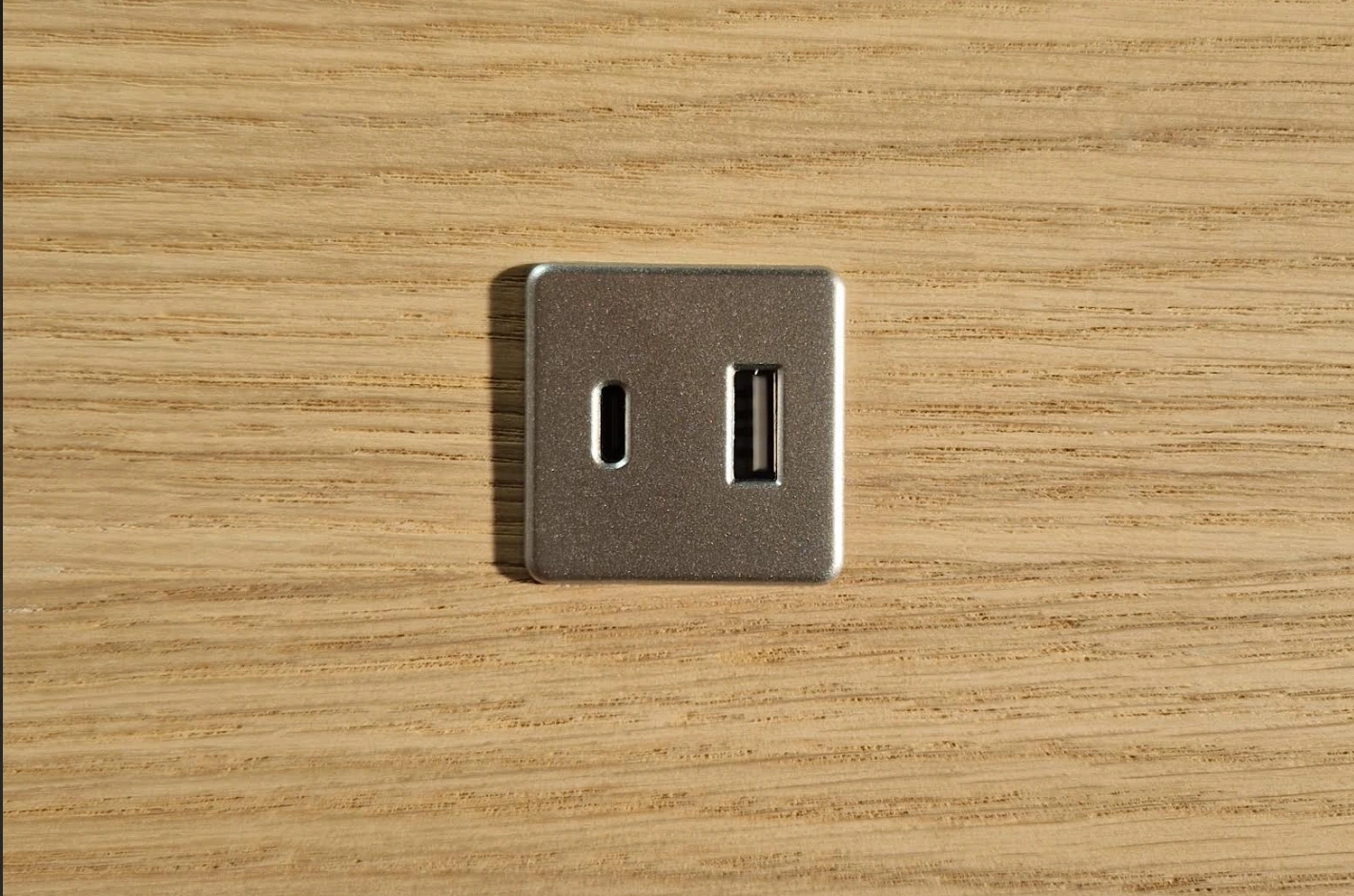 Zilveren USB-lader met USB-A en USB-C ingebouwd in een eiken wandplank